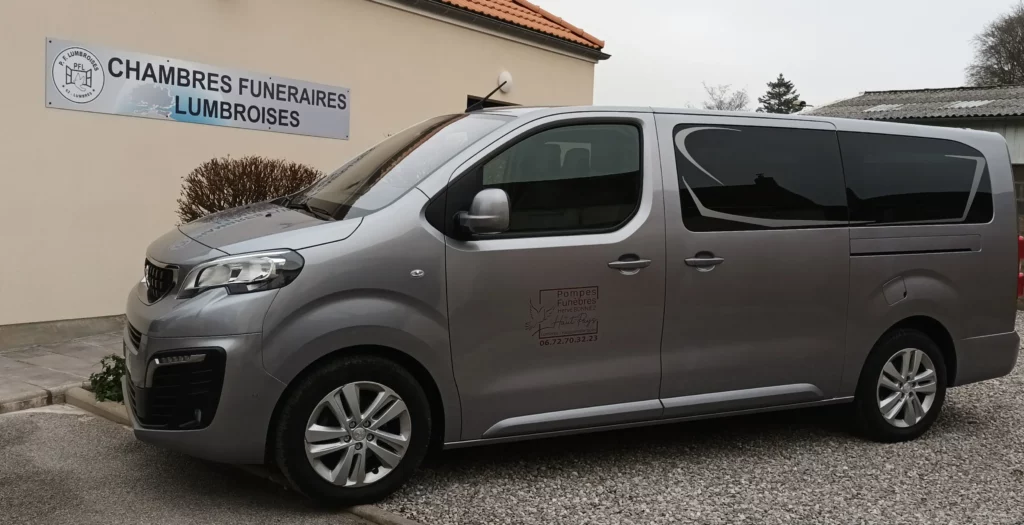 Fourgon funéraire gris stationné devant une chambre funéraire.