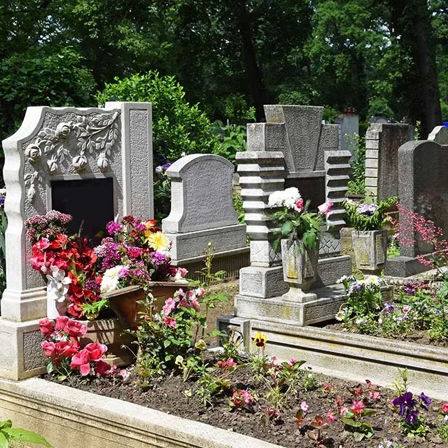 Tombes et stèles ornées de fleurs colorées dans un cimetière verdoyant.