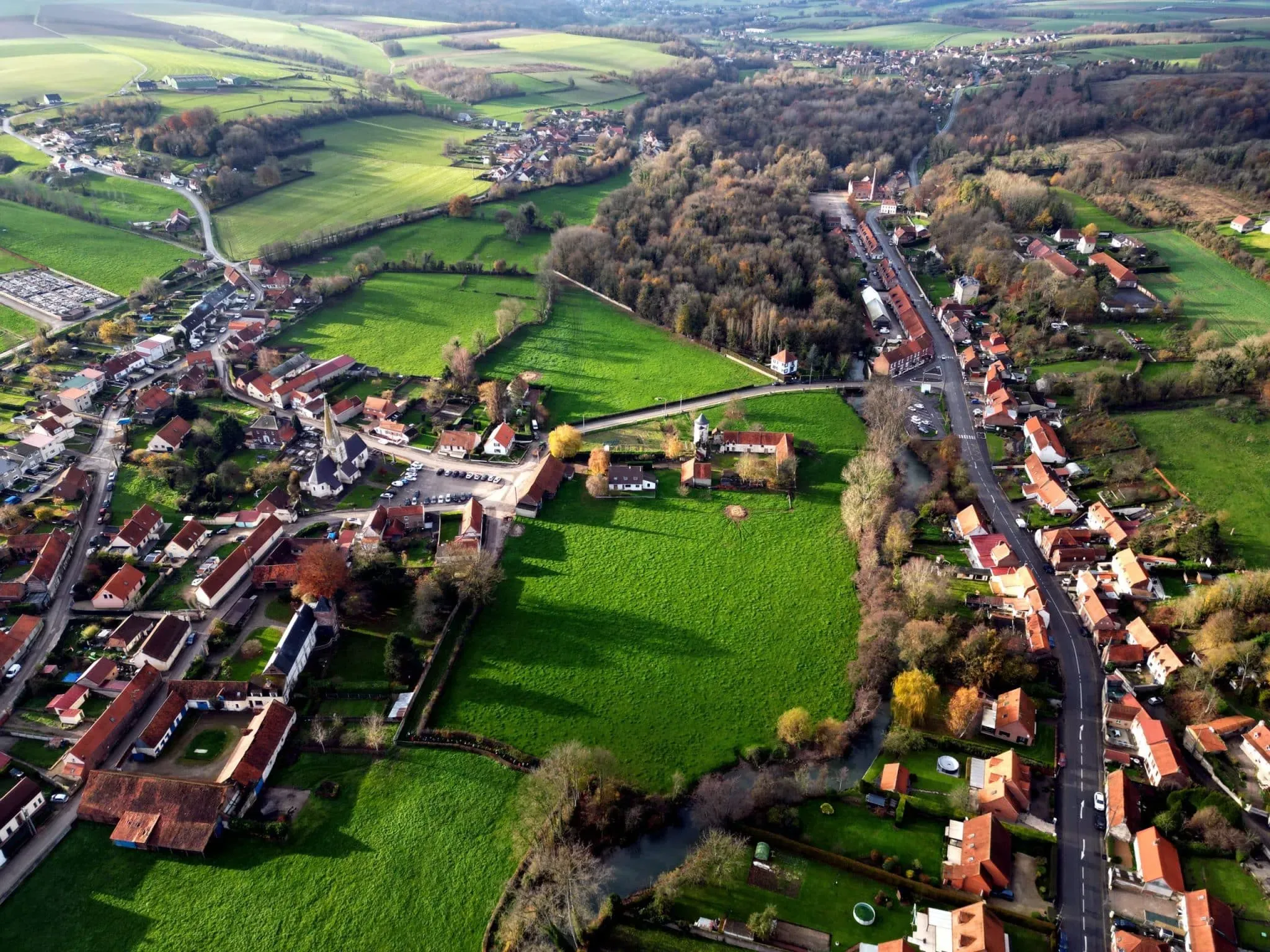 Vue aérienne d'un village rural entouré de champs verdoyants.